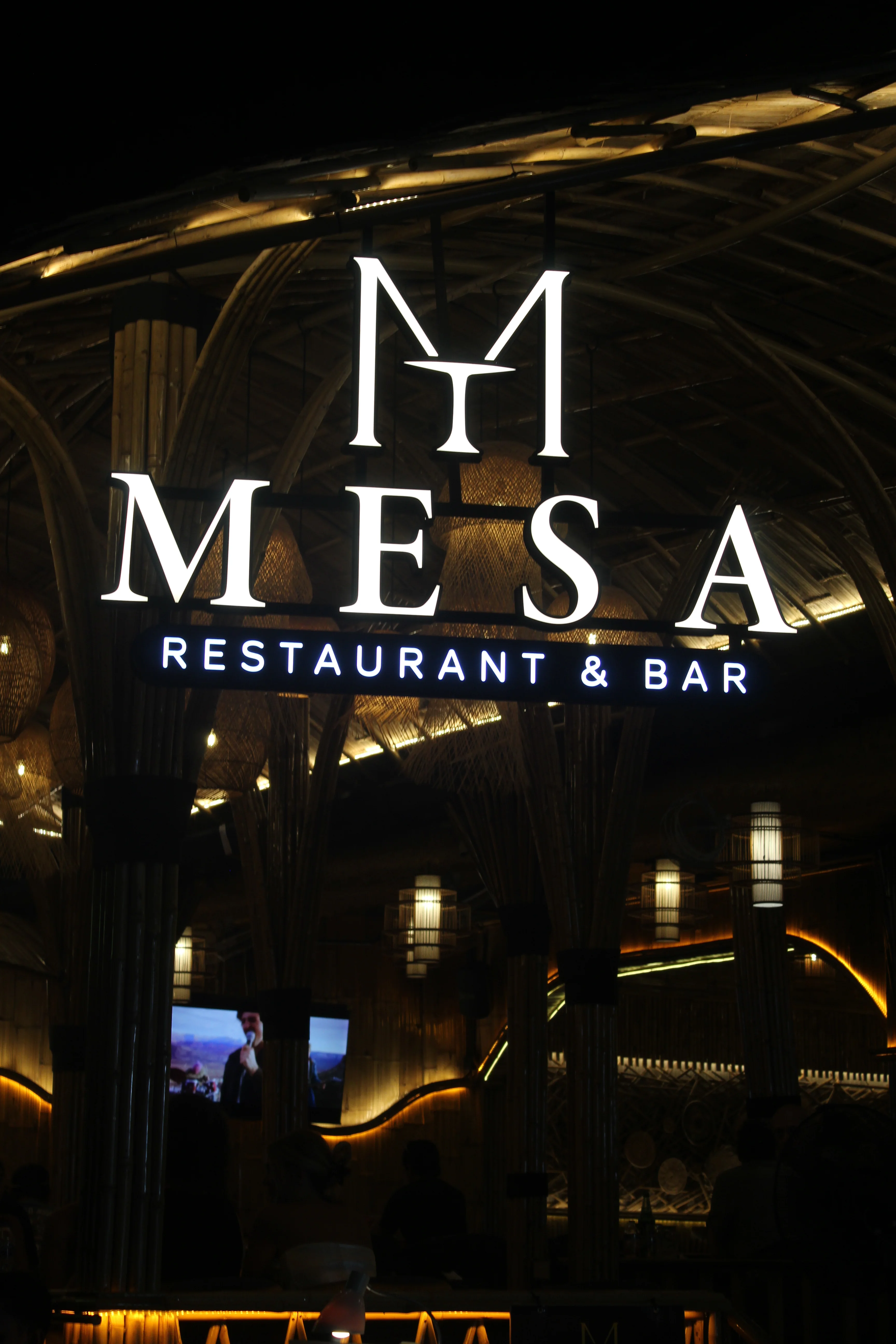 The illuminated bamboo exterior of MESA Restaurant & Bar at night