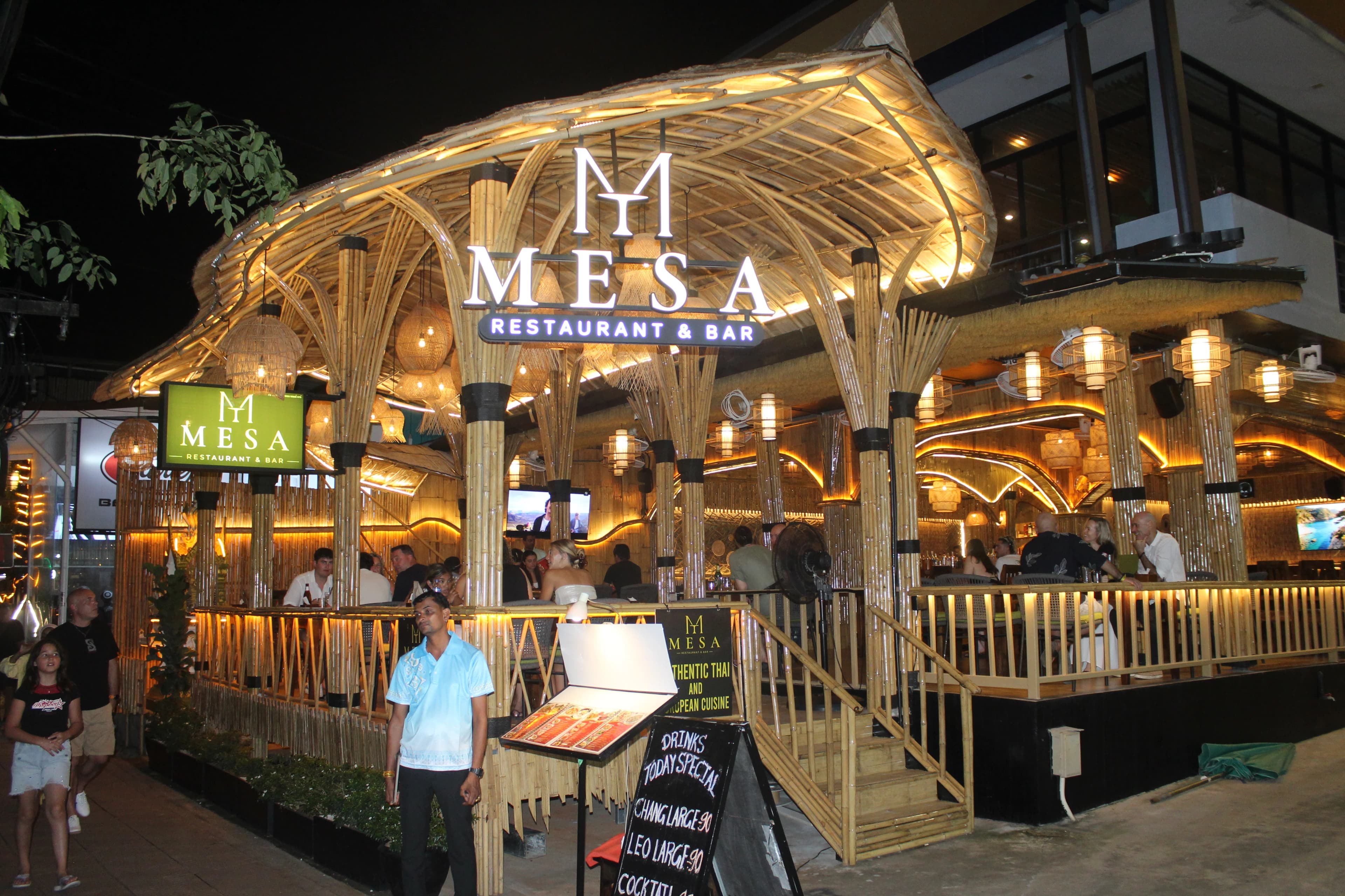 The MESA bamboo pavilion lit up at night, seen from the street