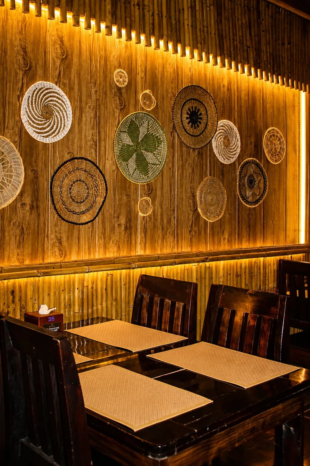 A bamboo-lit table beneath MESA's woven wall art